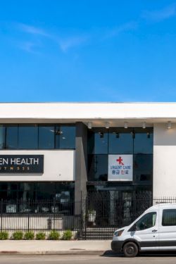 A storefront clinic building with signs for Seven Health Fitness and Urgent Care, under a clear blue sky.