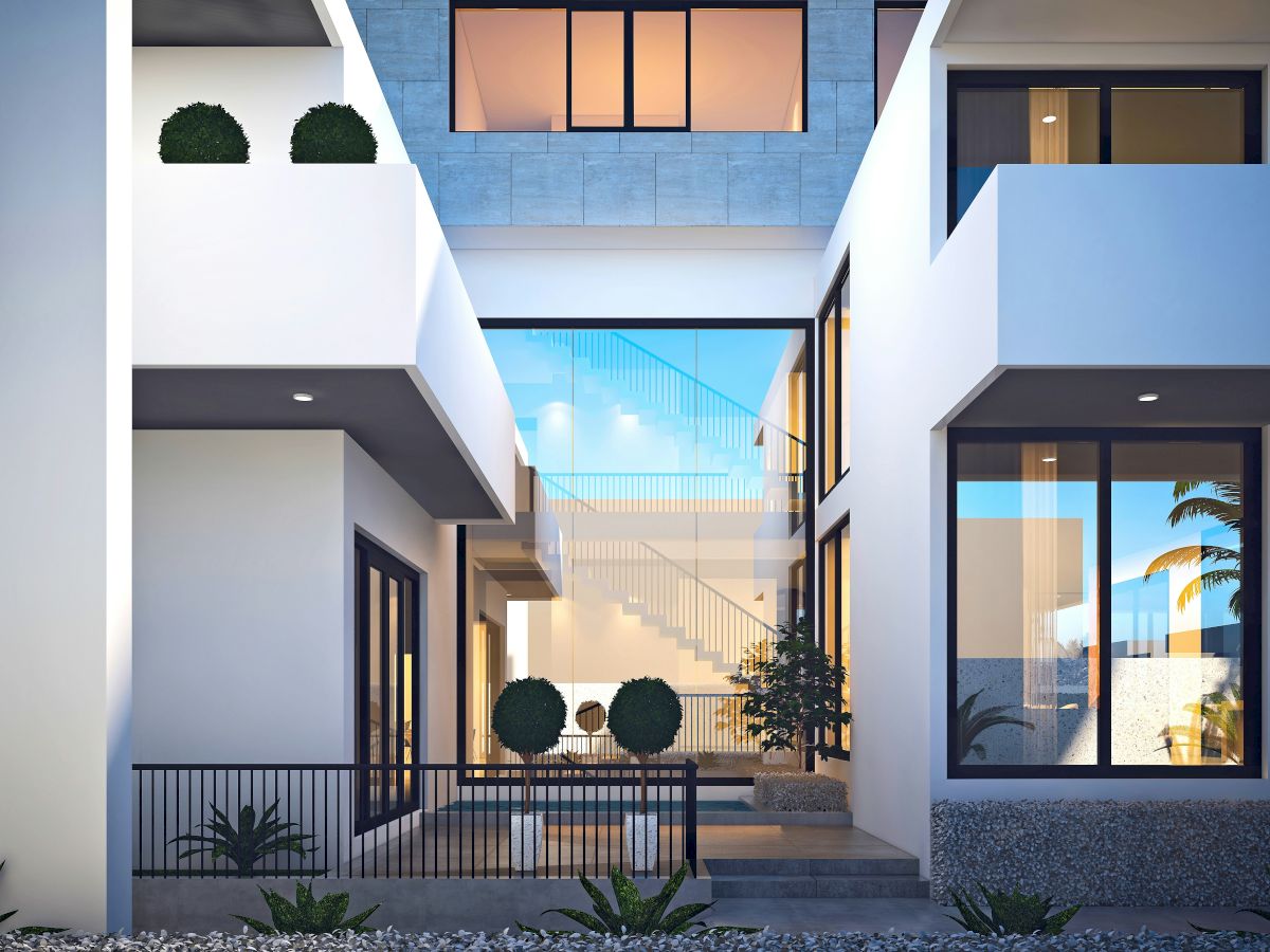 A modern courtyard interior with white walls, glass windows, a central staircase, potted plants, and a view of palm trees and sky.