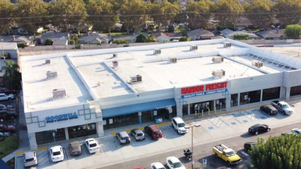 Aerial view of a shopping center with Harbor Freight and Goodwill stores, cars parked in front.